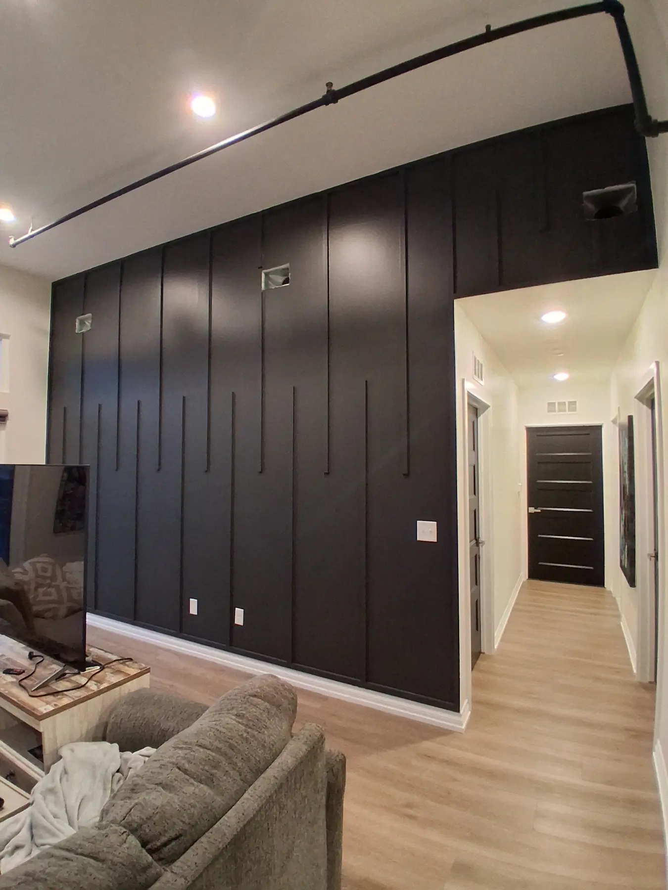 A black board-and-batten accent wall with staggered vertical battens running down a hallway